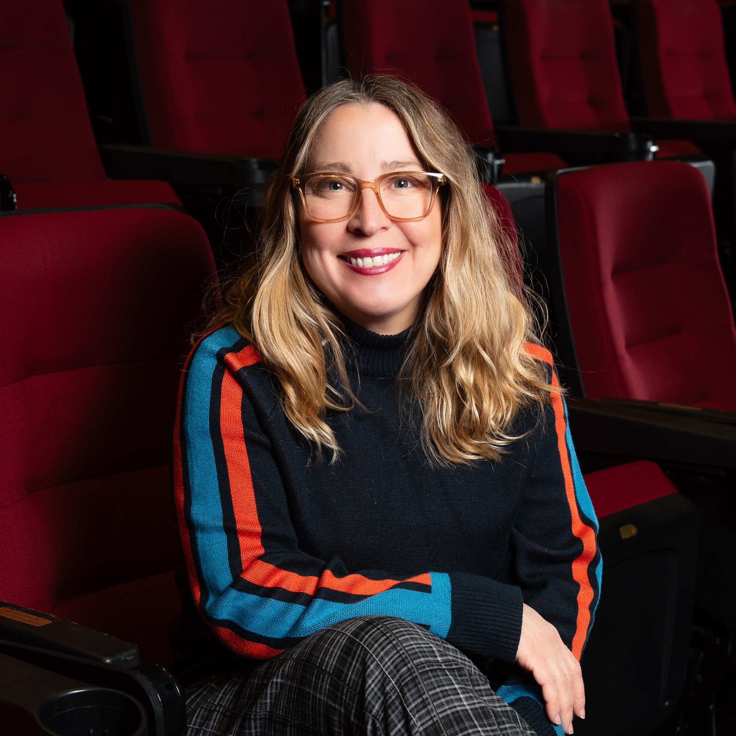 Photo of Carla Tisdale sitting in a red theater chair