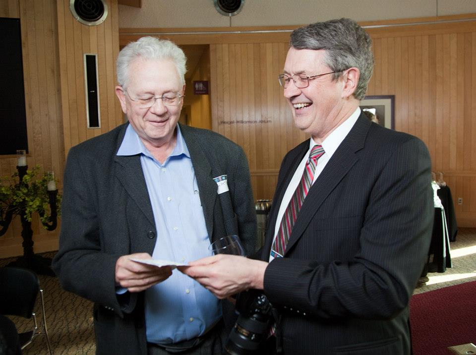 Two men holding a piece of paper smiling