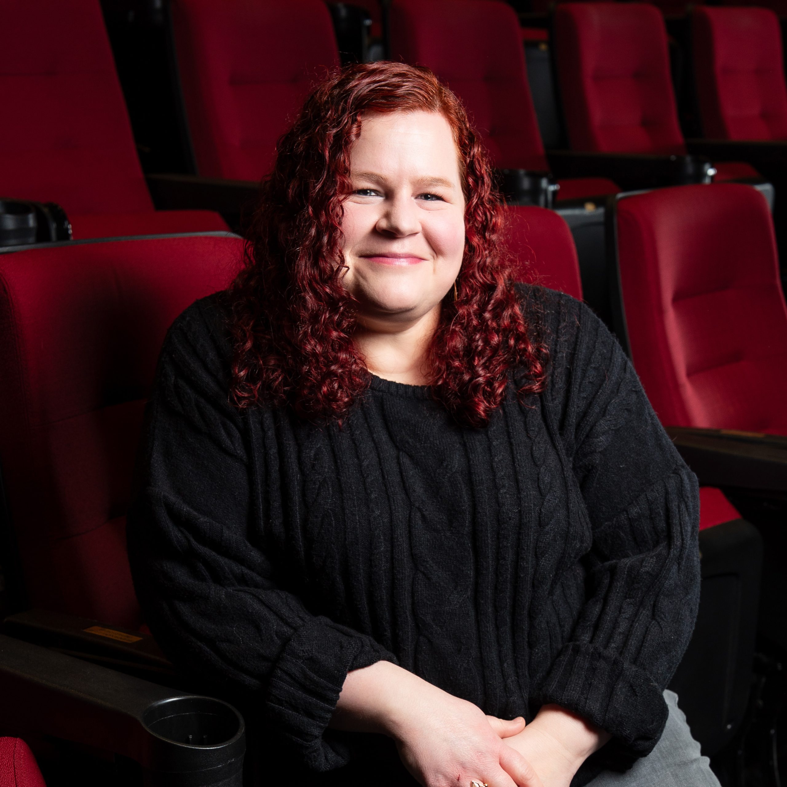 Photo of Meghan Stratman sitting in a red theater chair