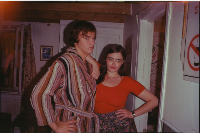 A scene from Mile End Kicks. Chevy (Stanley Simons) and Grace (Barbie Ferreira) pose for a photo in a living room.