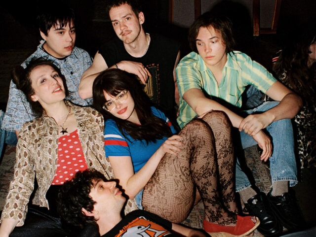 A scene from Mile End Kicks. Six young adults sit in a group.