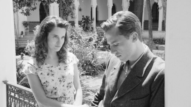 A man and woman stand in a flowering garden. Black and white.