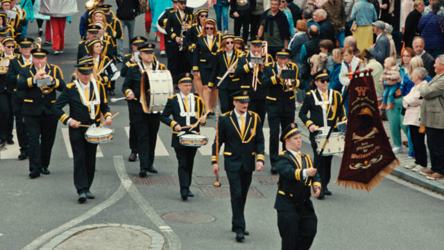 A scene from Emmanuel Courcol’s THE MARCHING BAND. A marching band of men and women of various ages marches in a parade.