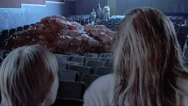 A blob covers seats in a movie theater in a scene from The Blob.