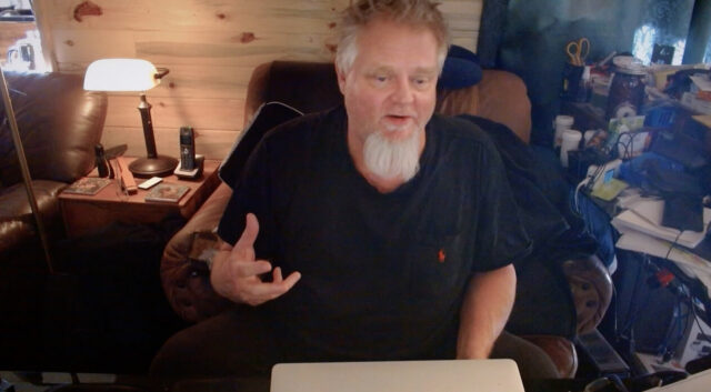 Kevin Cowan sits at a desk in a scene from Coffee with Claude.