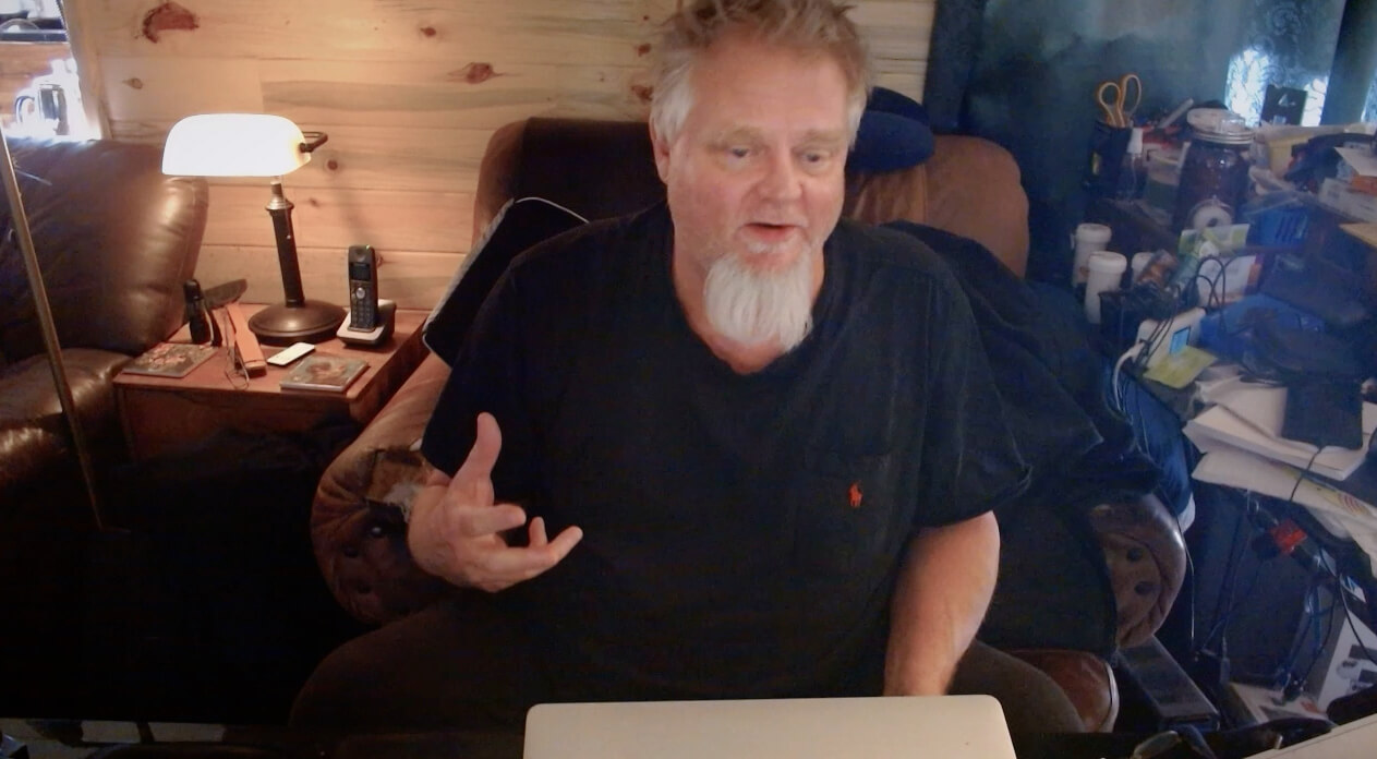 Kevin Cowan sits at a desk in a scene from Coffee with Claude.