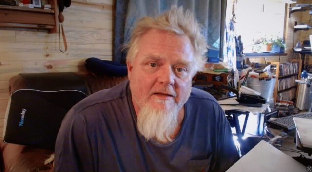 Kevin Cowan sits at a desk in a scene from Coffee with Claude.
