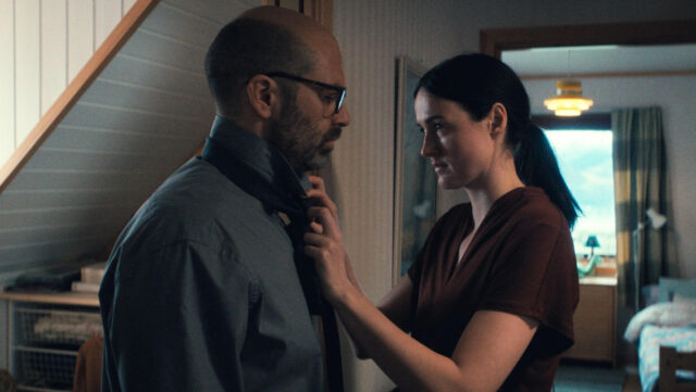 Renate Reinsve and Sebastian Stan stand in an interior hallway in a scene from Fjord.