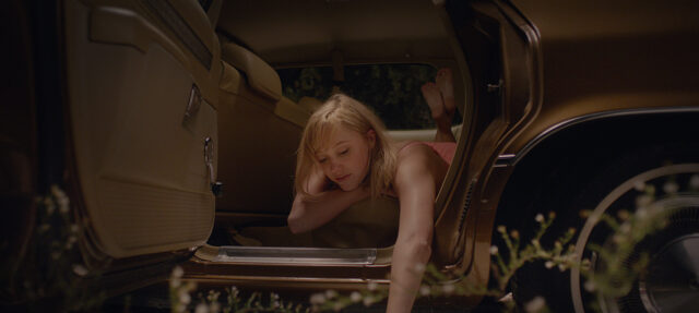 Maika Monroe leans out of an open car door in a scene from It Follows.