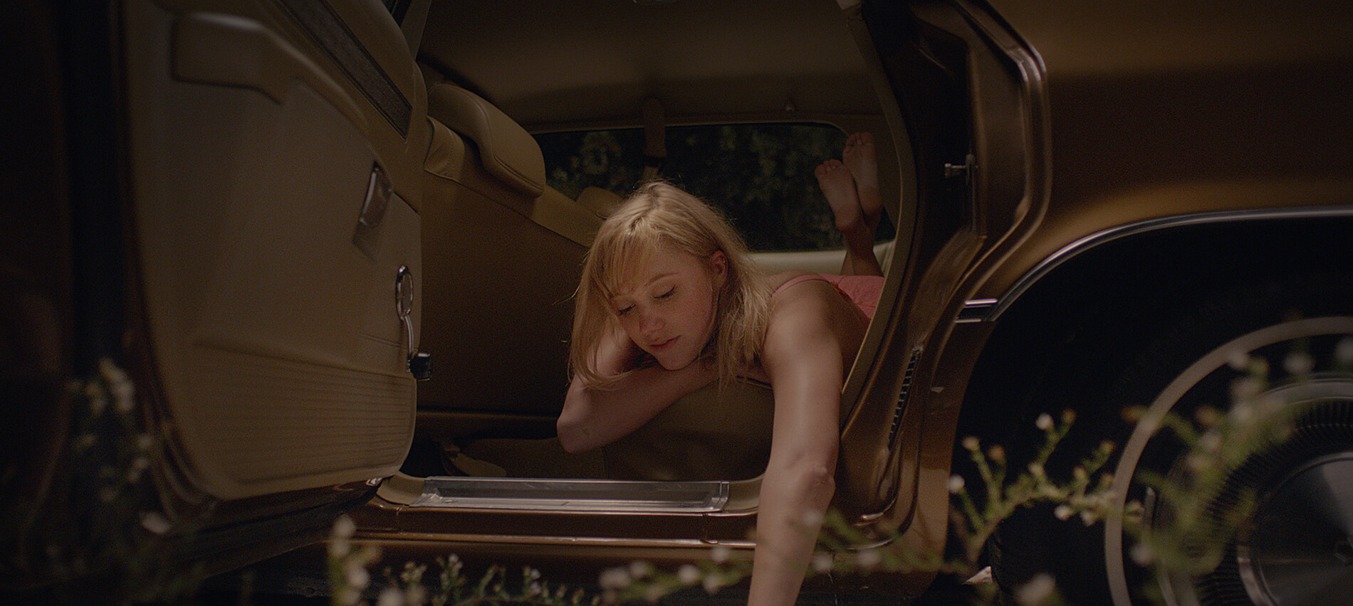 Maika Monroe leans out of an open car door in a scene from It Follows.