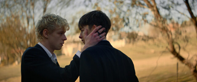 A teen boy (Stacy Clausen) touches the cheek of another boy (Joe Bird) in a scene from Leviticus.
